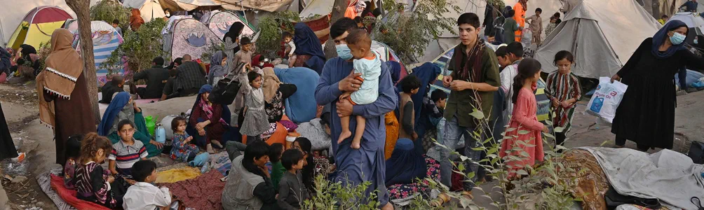 Internally displaced Afghan families, who fled from Kunduz, Takhar and Baghlan province due to battles between Taliban and Afghan security forces, sit in front of their temporary tents at Sara-e-Shamali in Kabul on August 11, 2021.
