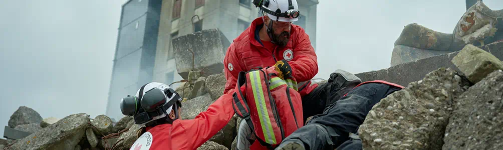 Red cross responders search for survivors in the rubble after an earthquake.